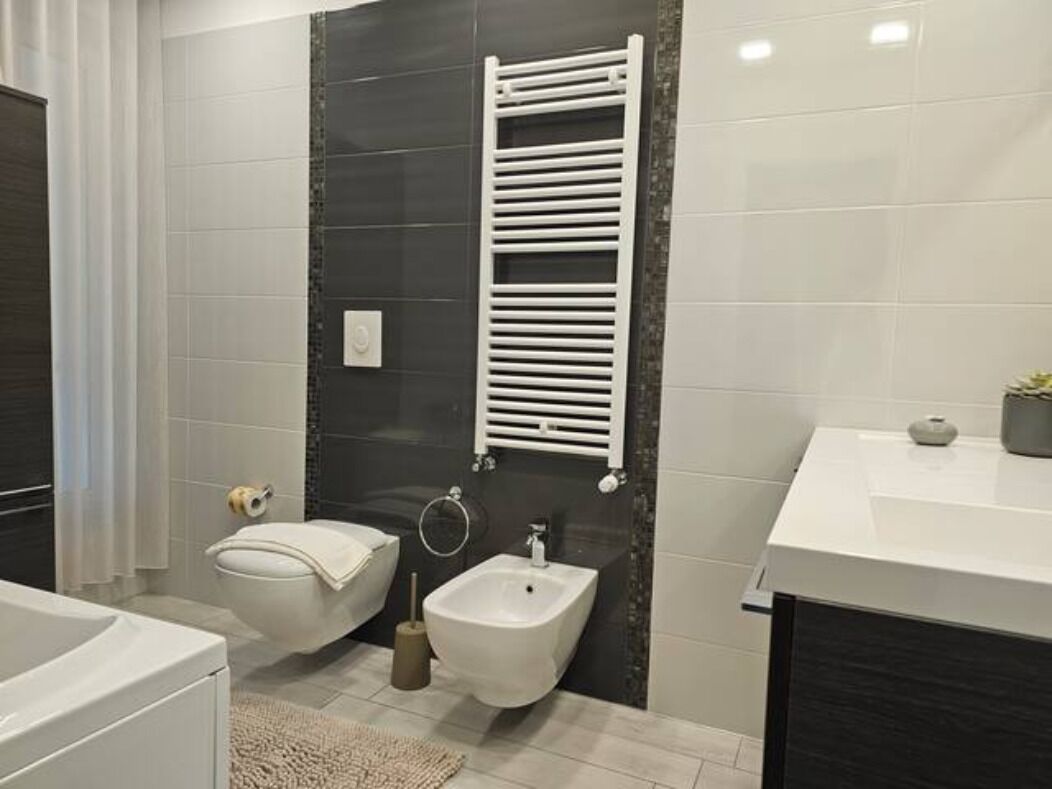 A modern bathroom with a bathtub, bidet, and a white sink.