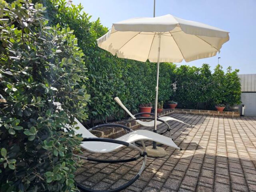 Eine Terrasse mit Sitzgelegenheiten und einem großen Sonnenschirm.