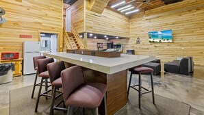 A modern kitchen with a central island, bar stools, a microwave, and a refrigerator.
