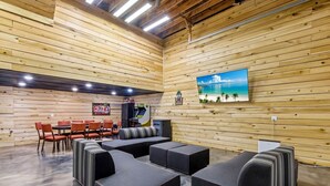 A wooden-paneled room with a dining area, sofas, and a painting of a beach scene.