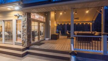 A covered deck with outdoor seating, a stone pillar, and a wooden deck.