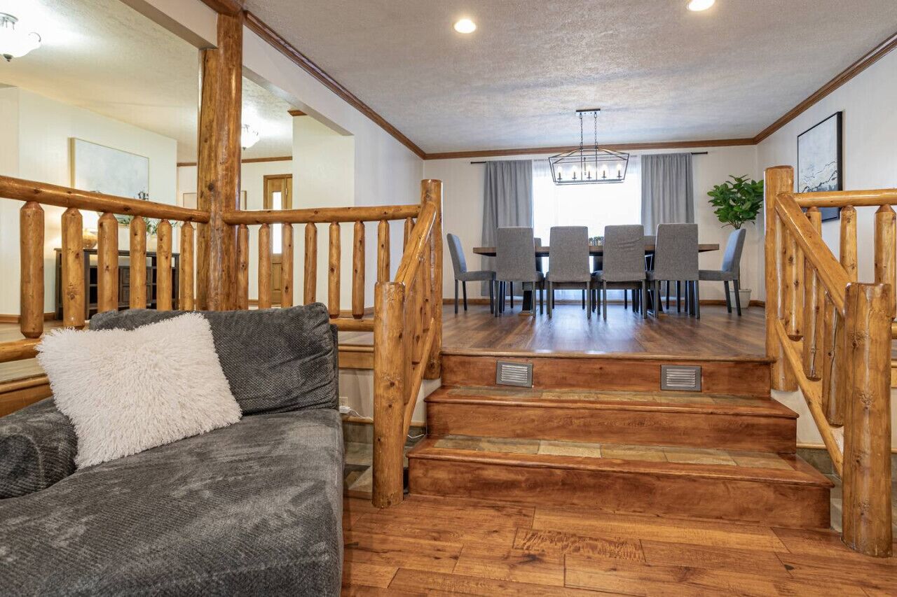 Una escalera de madera conduce a un comedor con una mesa y sillas.
