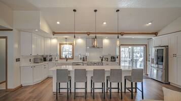 A modern kitchen with white cabinets, a central island with bar stools, and stainless steel appliances.