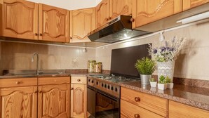 Una cocina con armarios de madera, un lavamanos de acero inoxidable, una estufa y un jarrón decorativo con plantas.