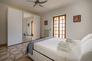 A bedroom with a bed, a ceiling fan, a window, and a radiator.