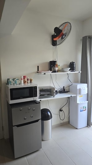 Eine Küchenzeile mit Mikrowelle, Toaster, Kühlschrank und einer kleinen Mülltonne.