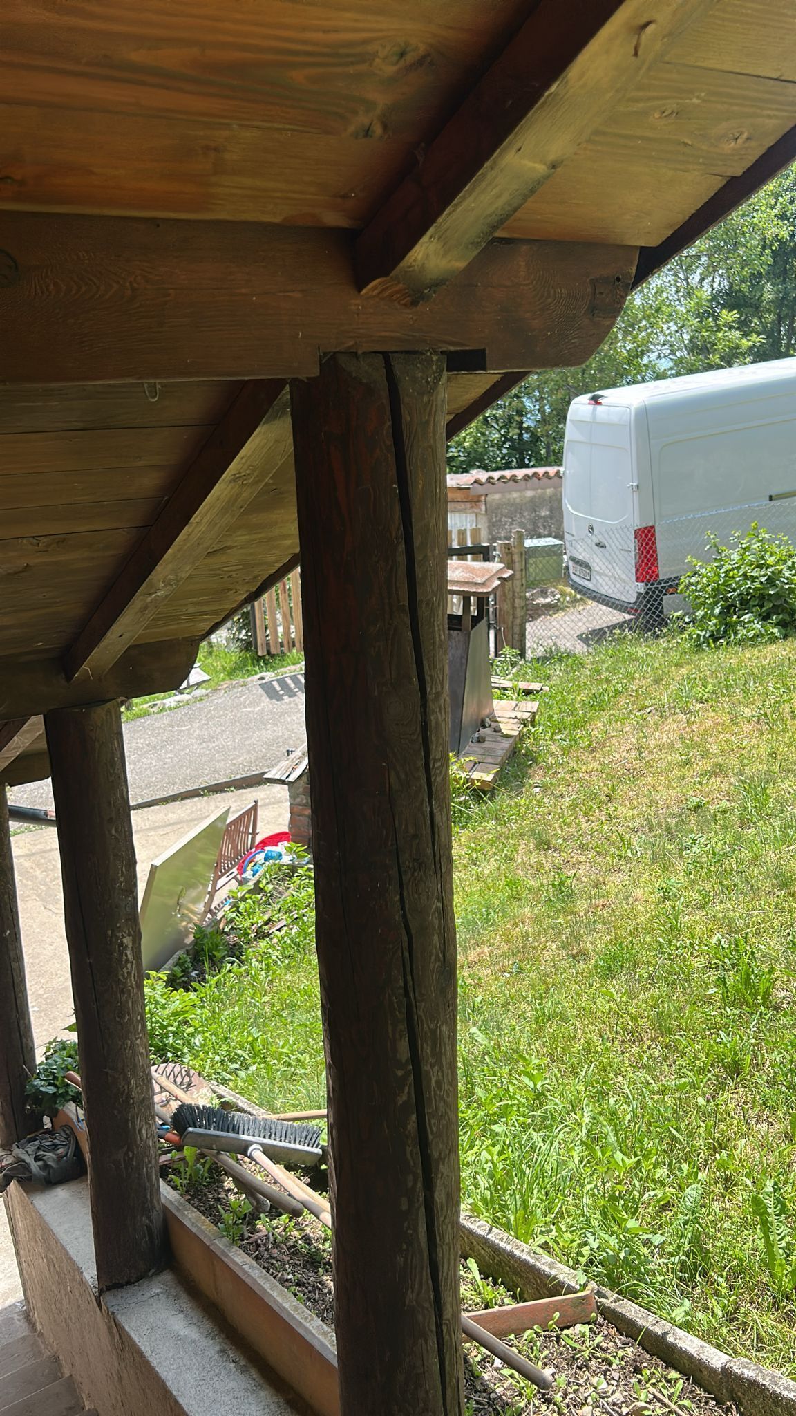 A wooden structure with a view of a grassy area and a parked vehicle.