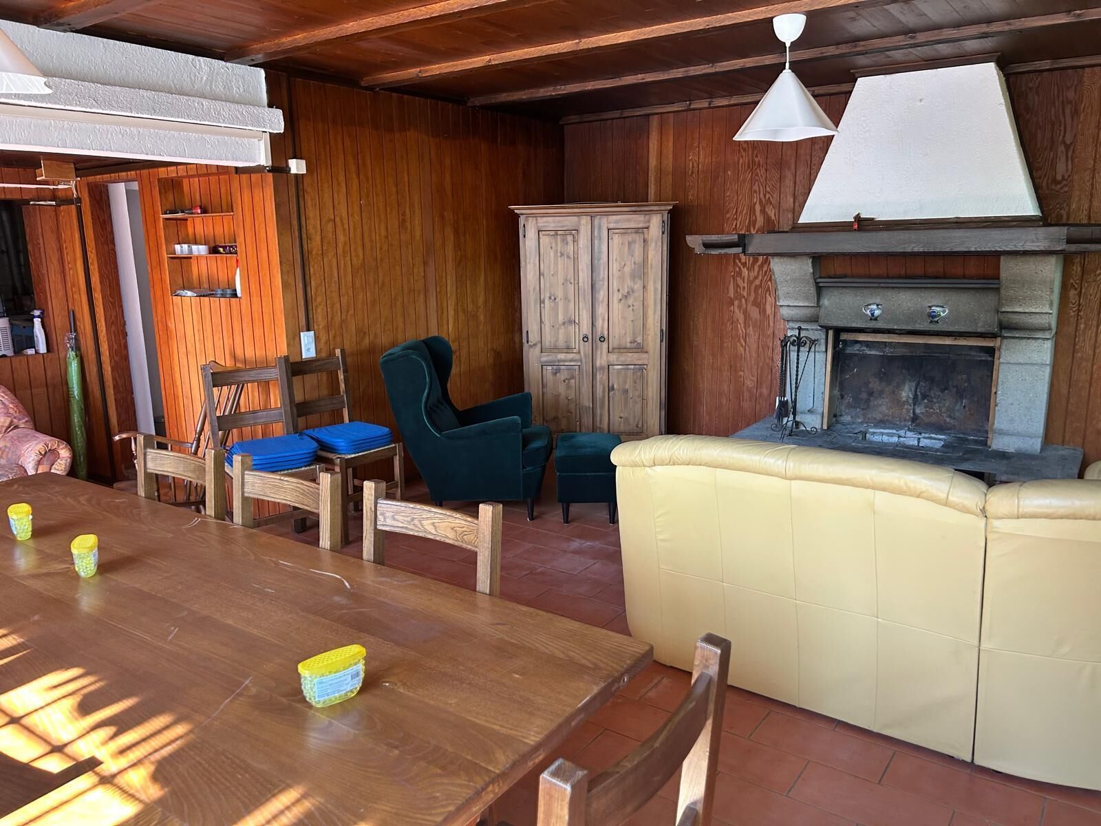 A cozy room with a wooden dining table, chairs, a cushioned bench, a cabinet, and a fireplace.