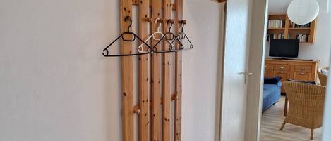 A hallway with a ski rack, a radiator, and a wicker chair.