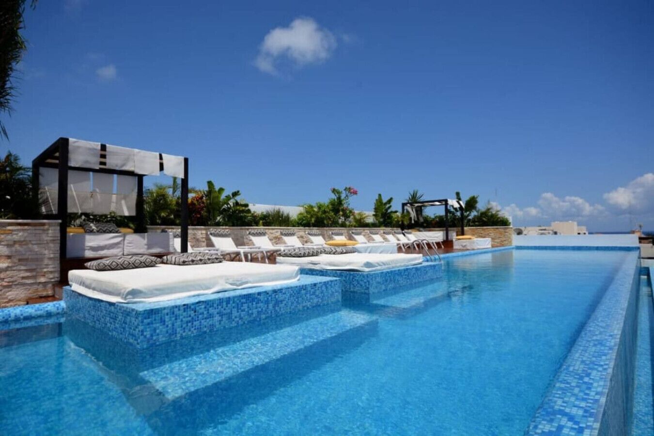 Une piscine avec des chaises longues et un espace de détente abrité.