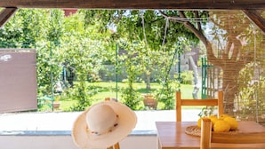 Une table en bois sur laquelle sont posés un panier tressé et des citrons, une chaise en osier et un chapeau de paille.