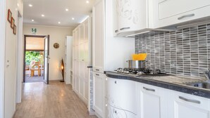 Une cuisine moderne avec des meubles blancs, une cuisinière à gaz et un évier en acier inoxydable.