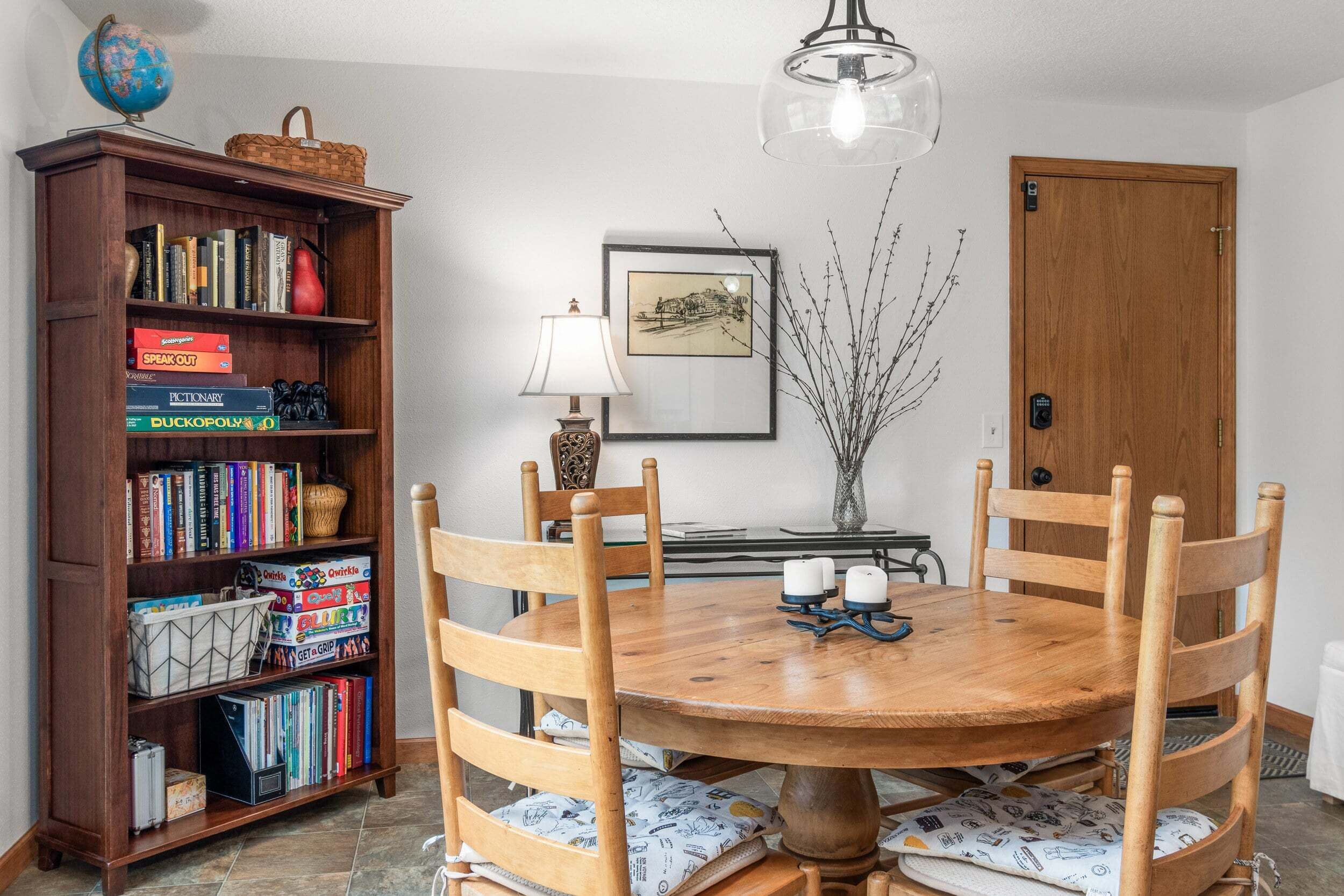 Un comedor con una mesa de madera, sillas, una estantería, un globo terráqueo y una lámpara.