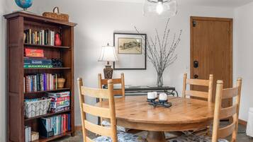 Un comedor con una mesa de madera, sillas, una estantería, un globo terráqueo y una lámpara.