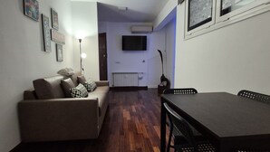 A compact living space with a sofa, a dining table, and a TV mounted on the wall. - Aroma Vaticano - Penthouse in residential area near the Vatican (60sqm-650sqft) (Roma)