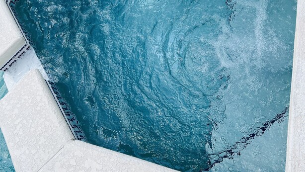 A rectangular swimming pool with a textured white edge and a mosaic tile border.