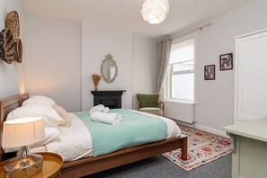 A neatly arranged bedroom with a bed, bedside lamp, and a small table. - (Boscombe)