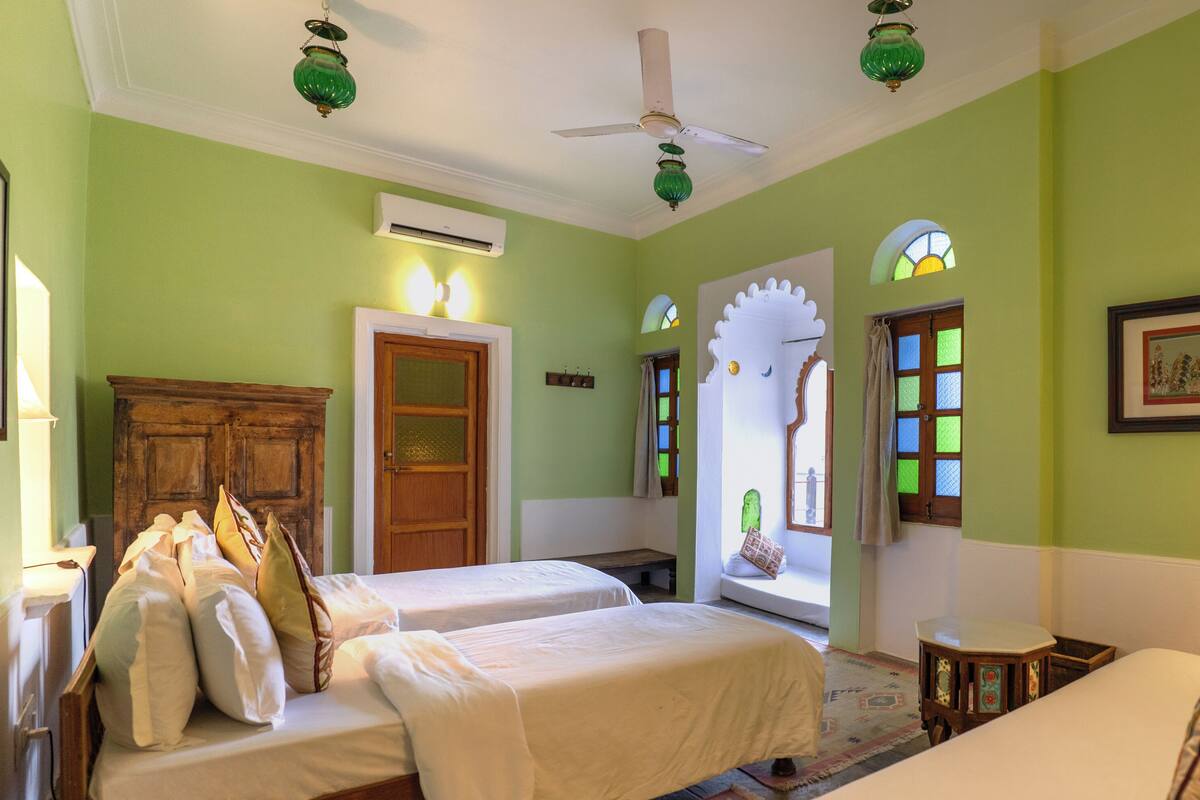 A room with two beds, a wooden wardrobe, a ceiling fan, and a window with a view.