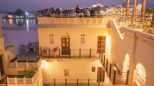 A multi-story building with a courtyard, balconies, and a view of the water. - KANKARWA HAVELI (Udaipur)