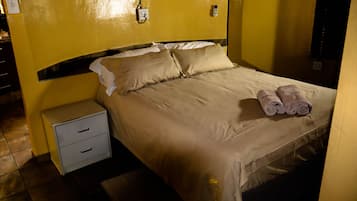 Quarto de hotel com uma cama, mesa de cabeceira e toalha dobrada na cama.