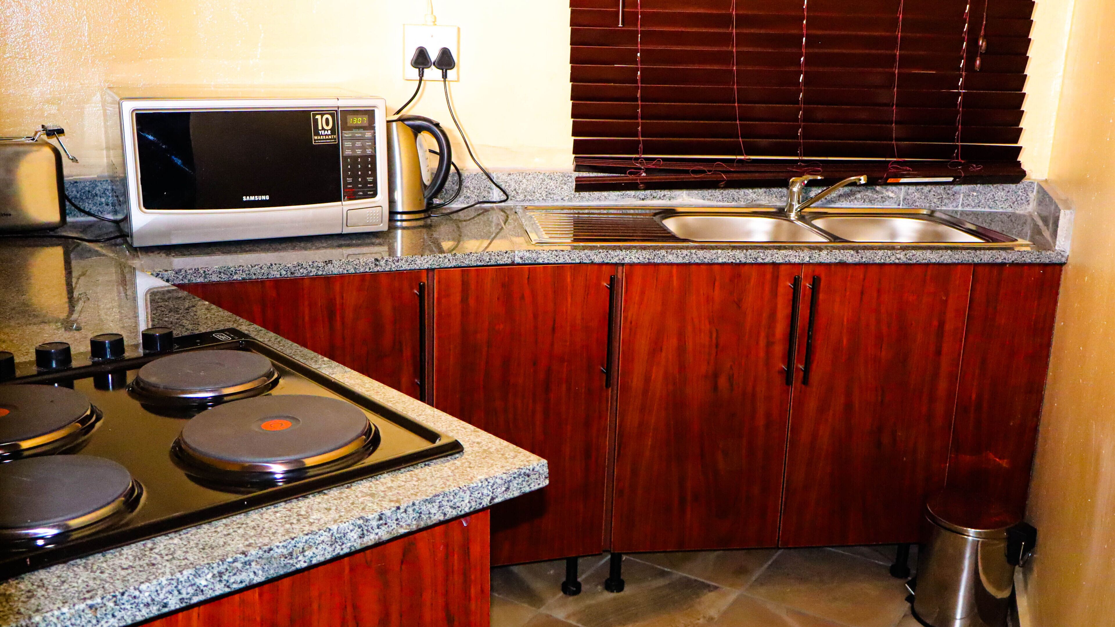 A compact kitchen with a microwave, stove, sink, and wooden cabinets.