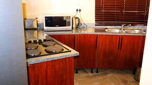 A kitchen with a stove, microwave, and sink. - Self Catering Chalets - Manyeleti (Manyeleti)