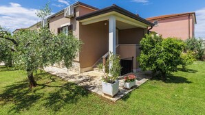 A two-story house with a covered patio, surrounded by well-maintained grass and olive trees. - Apartment Pino by Interhome (Umag)