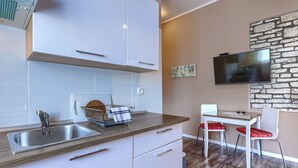 A compact kitchen with a sink, white cabinets, a wooden countertop, and a stone wall. - Apartment Pino by Interhome (Umag)