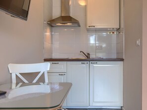 Functional kitchen with a stainless steel range hood, sink, and table.