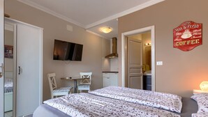 A hotel room with two beds, a TV, a small table, and a kitchenette. - Villa Ester by Interhome (Umag)