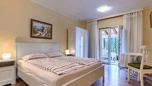 A bedroom with a bed, bedside lamps, a wardrobe, and a view to an outdoor area. - Villa Ester by Interhome (Umag)