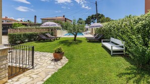 A backyard with a swimming pool, lounge chairs, and a stone pathway. - Villa Ester by Interhome (Umag)