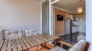 A dining area with a wooden table and benches, a kitchen with a TV, and a ceiling light. - Villa Ester by Interhome (Umag)