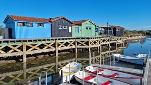 Une jetée en bois, bordée de bâtiments aux couleurs vives et où sont amarrés des bateaux à son extrémité.