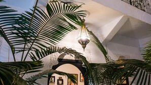 Un interno con un arco decorativo, un lampadario e piante verdi rigogliose.