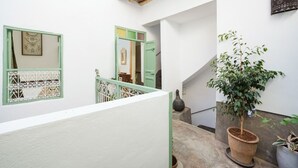 A clean, white interior with a wooden ceiling, a staircase with green railings, and a potted plant. - Riad Ghitaexclusif15 min de Jemaa El Fnaa (Marrakech)