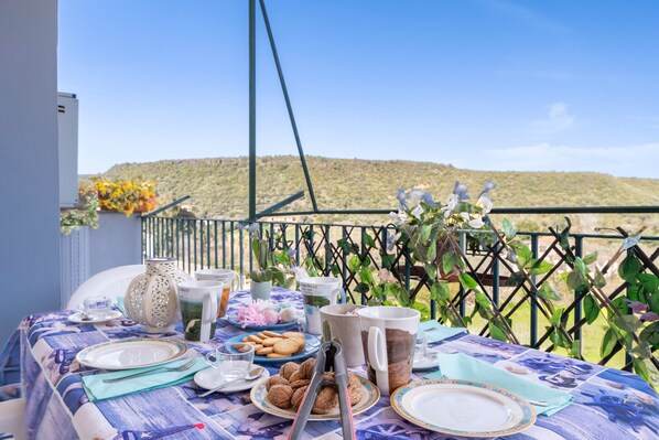 A table set for a meal with a view of a hilly landscape.