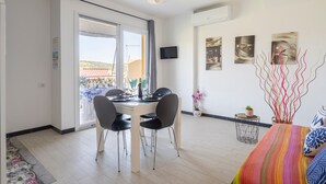 Uma sala de estar moderna com área de refeições, televisão e obras de arte nas paredes.