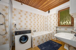 Un baño pequeño con lavadora, bañera y lavamanos.
