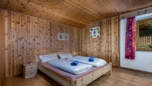 Ein Zimmer mit Holzwänden, einem Bett, einem Nachttisch und einem Fenster mit Blick.