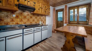 Eine Küche mit Holzausstattung, einem Herd und Bergblick durch große Fenster.