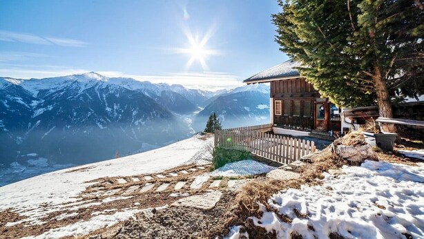 Eine Holzhütte mit Blick auf schneebedeckte Berge und einen klaren Himmel.