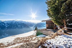 Una cabaña de madera con vistas a montañas nevadas y un cielo despejado.