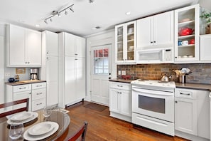 A modern kitchen with white cabinetry, a built-in microwave, and a stove.