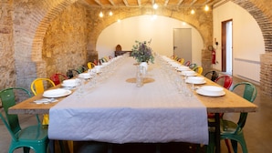 A long table set for a meal in a room with arched stone walls and wooden beams. - Villa 'Mas Tortós' with Mountain View, Private Garden and Barbecue (Palafolls)