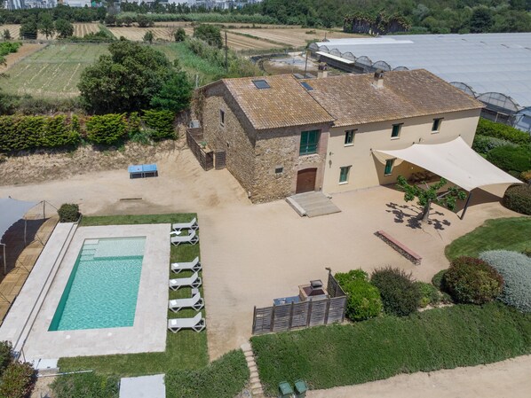 Un edificio grande con piscina, asientos al aire libre y un patio cubierto.