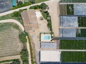 An aerial view of a property with a swimming pool, a large open area, and adjacent fields.