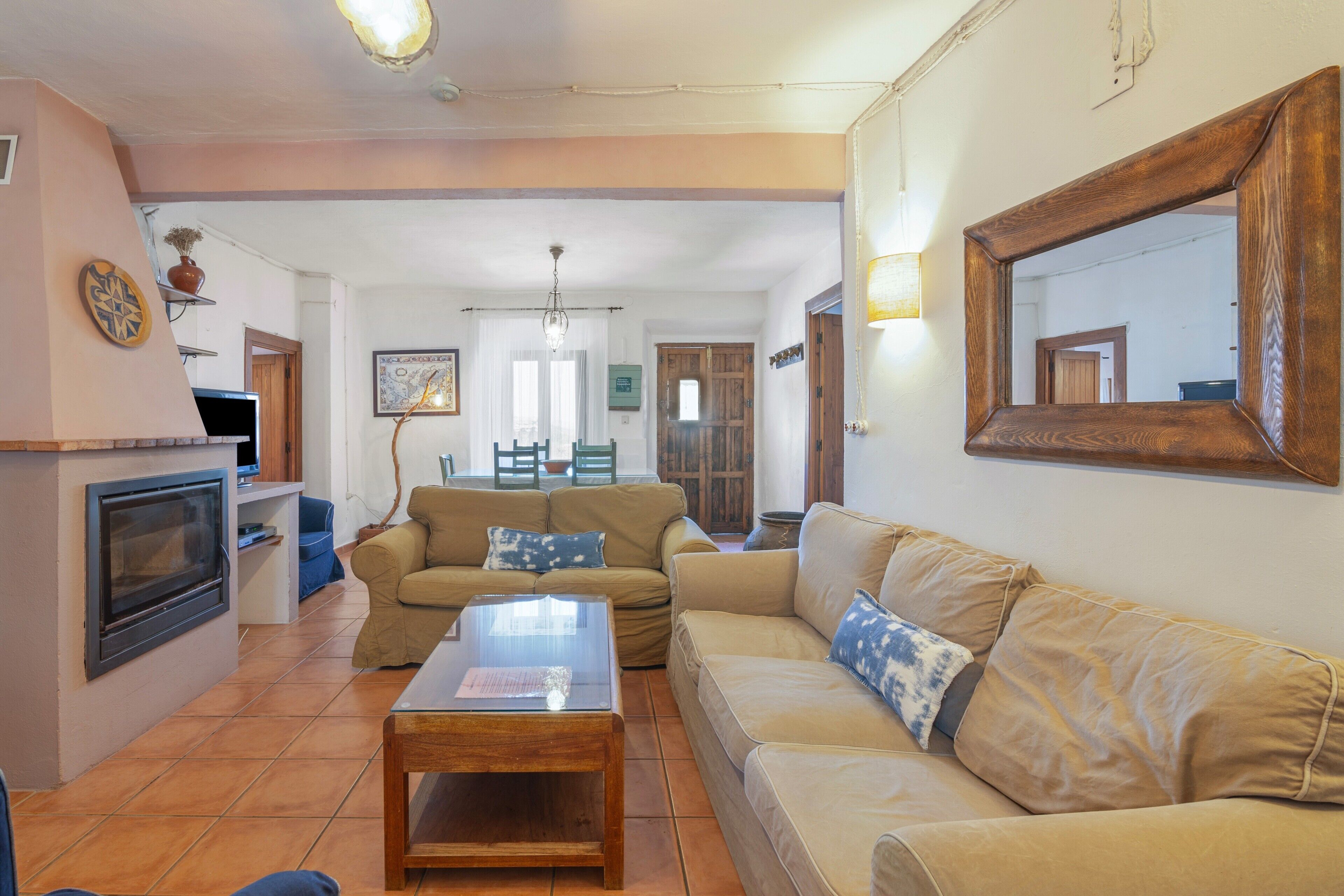 A living room with a sofa, a coffee table, a fireplace, and a dining area in the background.
