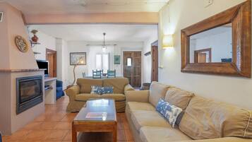 A living room with a sofa, a coffee table, a fireplace, and a dining area in the background.