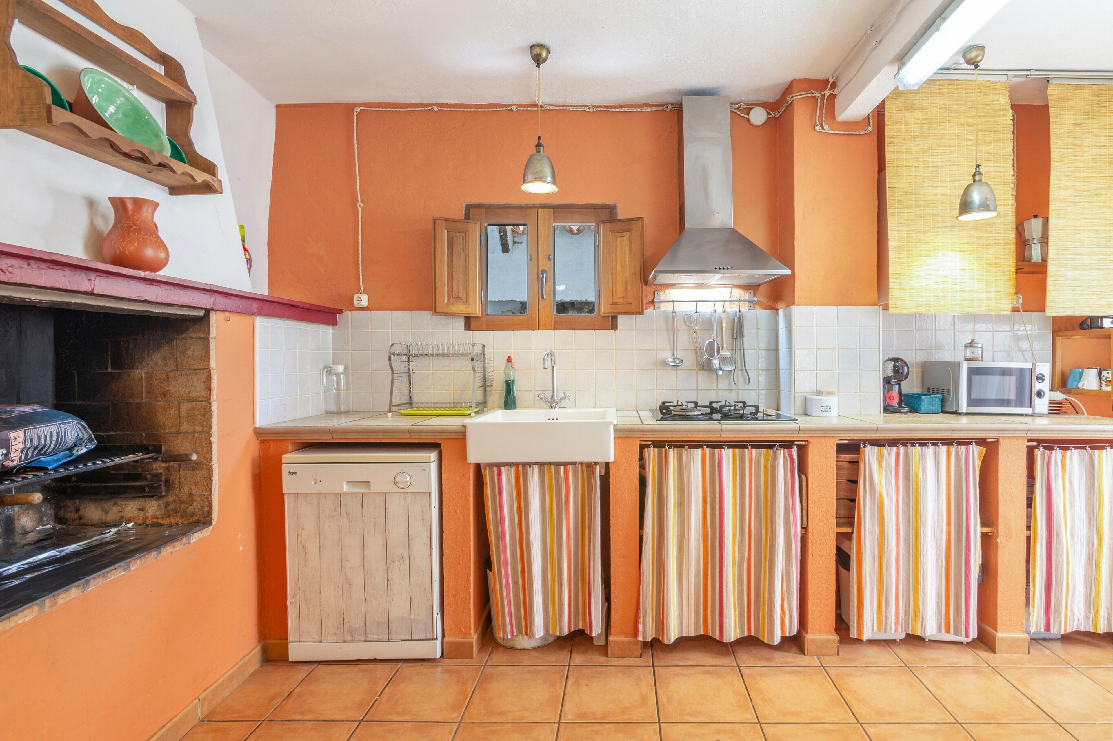A kitchen with a dishwasher, stove, microwave, and striped curtains.